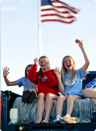Three girls eating Blue Bunny Treats and waving during a parade
