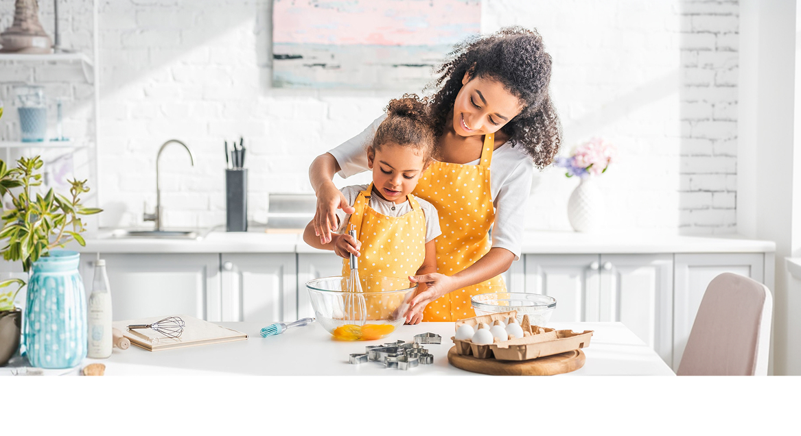 Mom helping her daughter stir the ingredients for a dessert