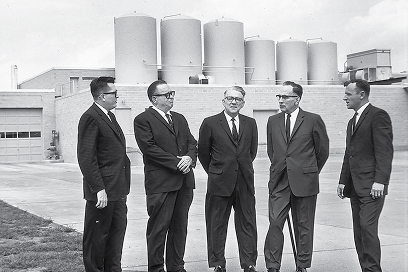 5 men in suits in front of the Blue Bunny Factory