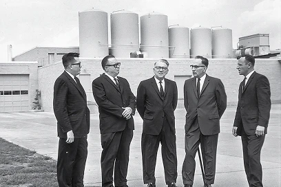 5 men in suits in front of the Blue Bunny Factory