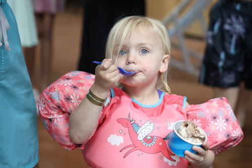Little girl in floaties eating ice cream
