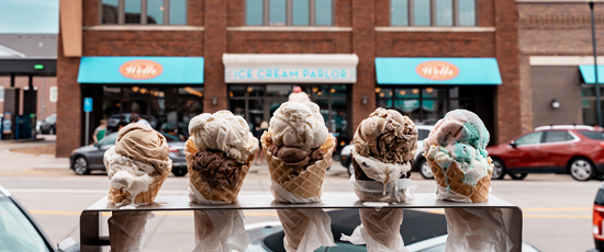 5 ice cream cones in a row in front of the parlor